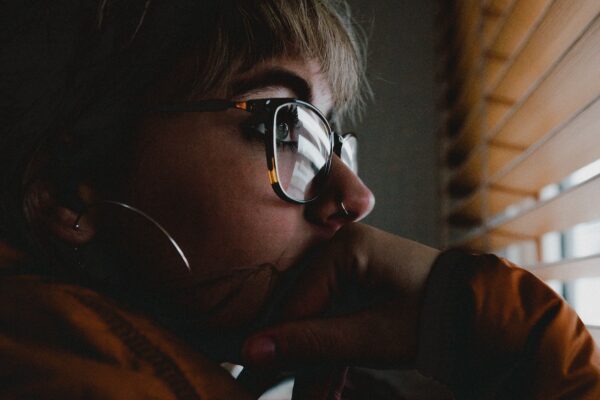 Pensive woman with glasses looking out of the window