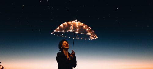 Woman holding illuminated umbrella at night
