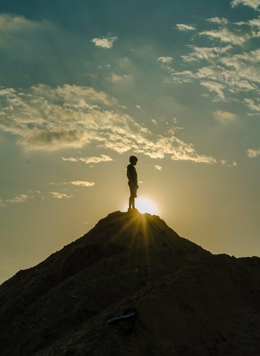 Man standing on mountain top with sun setting
